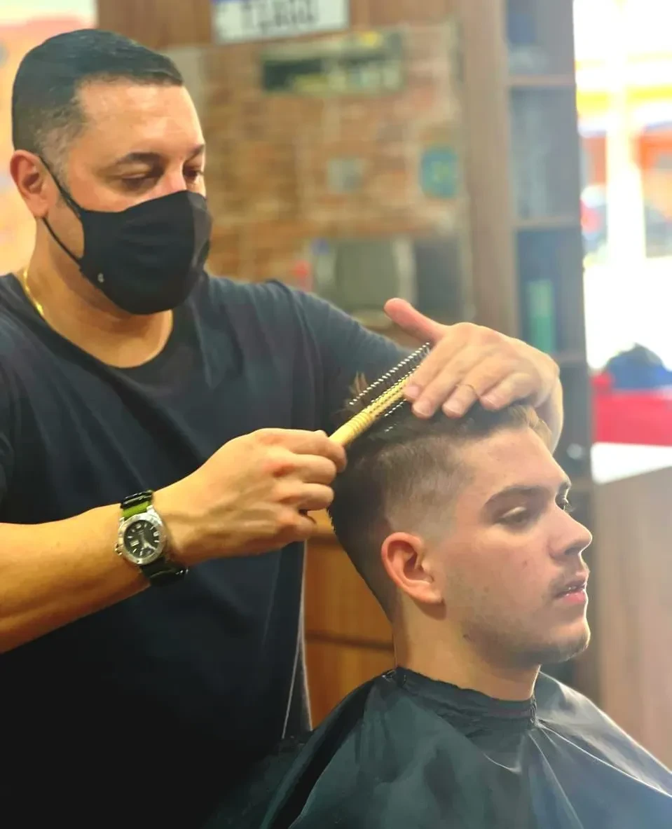 Barbeiro finalizando penteado com escova