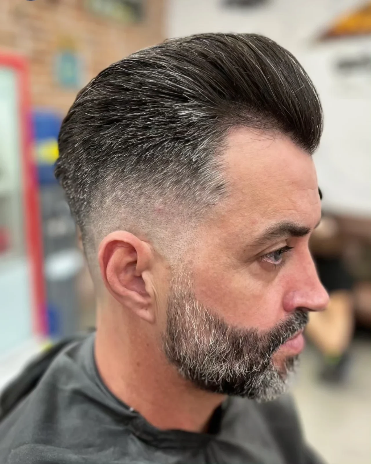 Corte pompadour com degradê e barba grisalha
