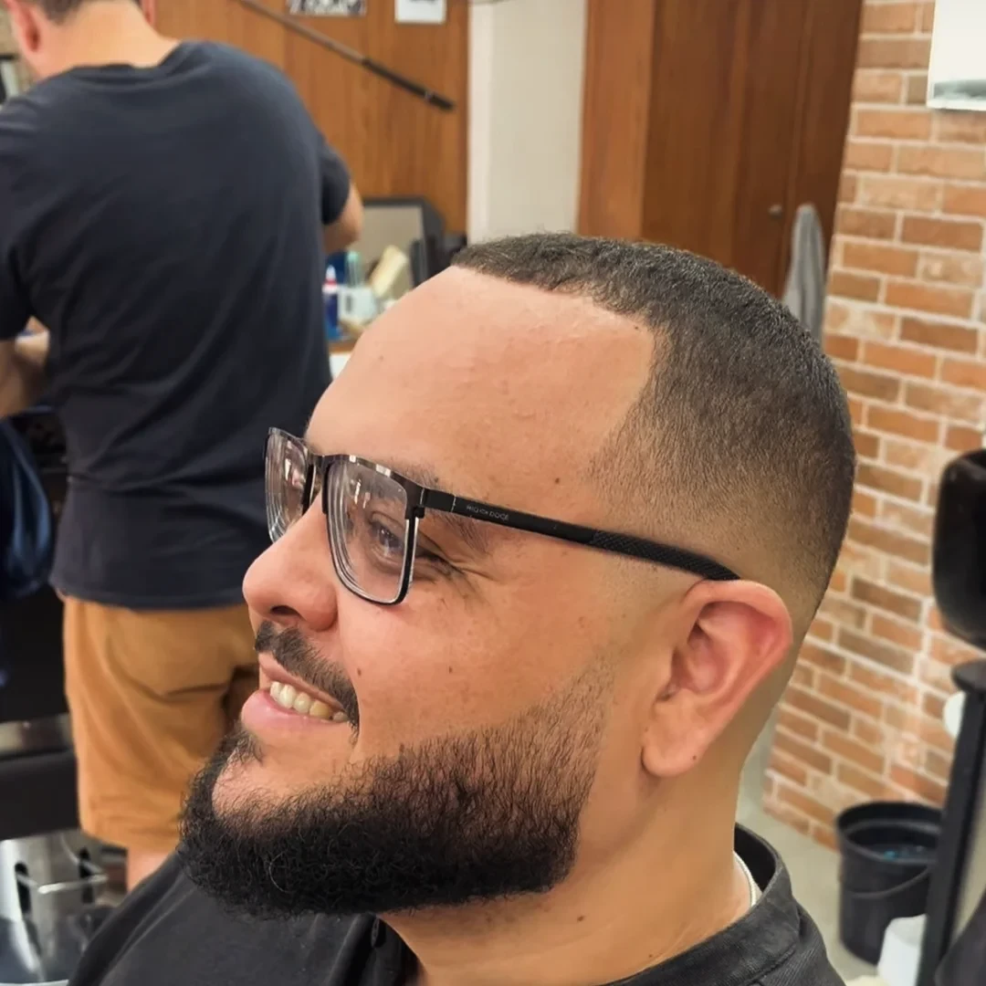 Cliente sorrindo com corte baixo e barba